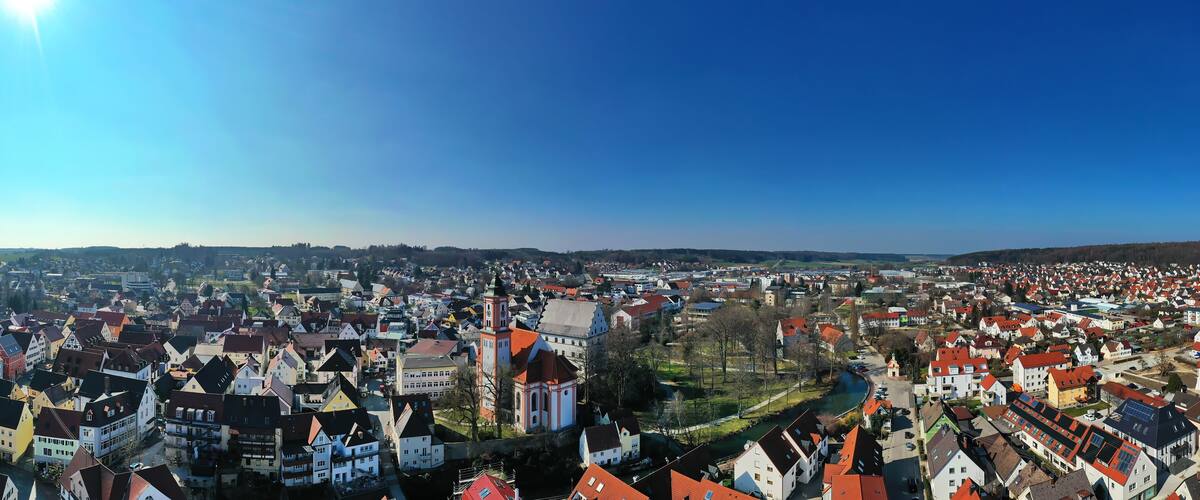 A panoramic view of a town with a river, historic buildings, and a prominent church tower.