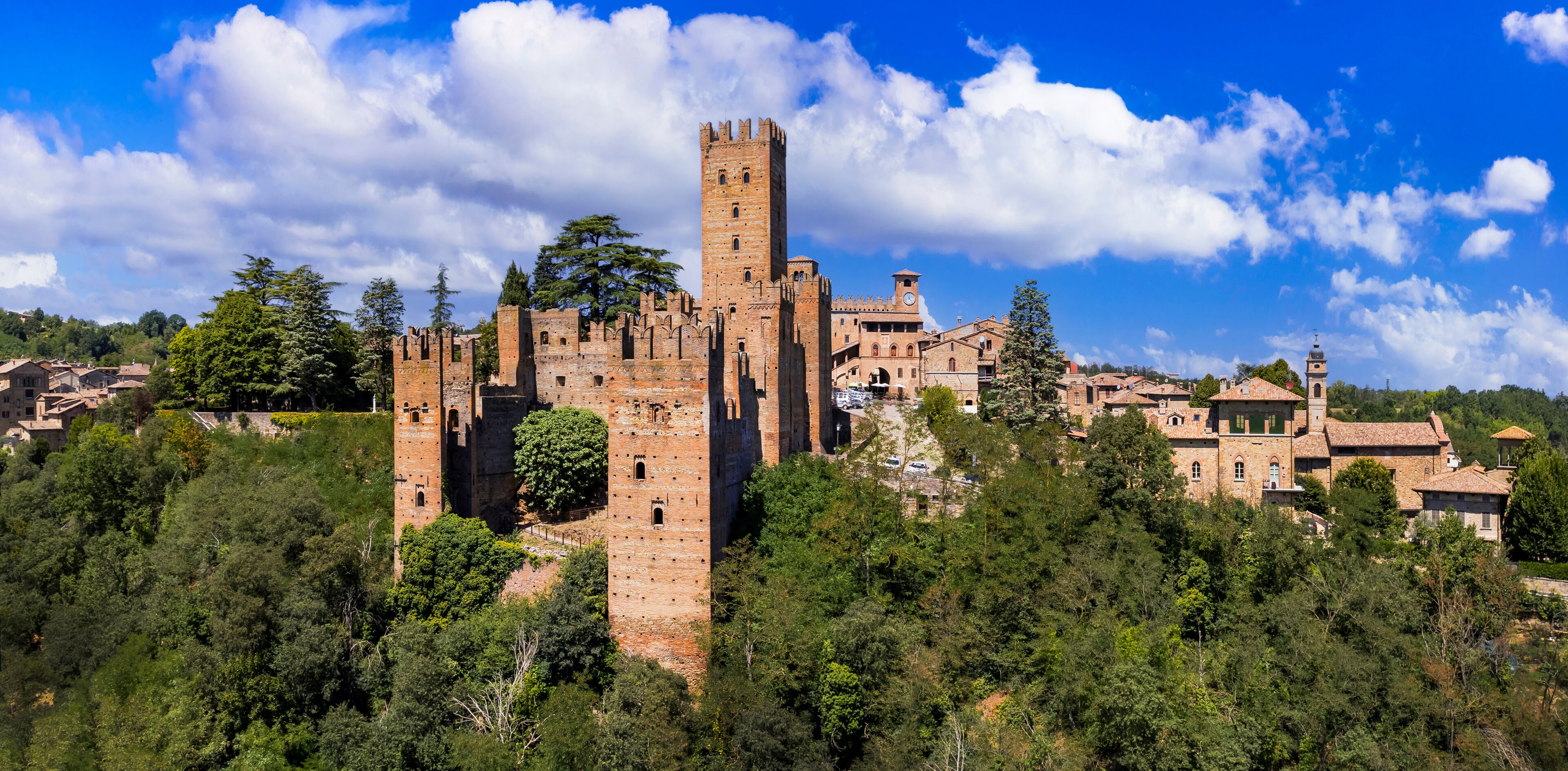 A historic castle surrounded by lush greenery and a clear blue sky.