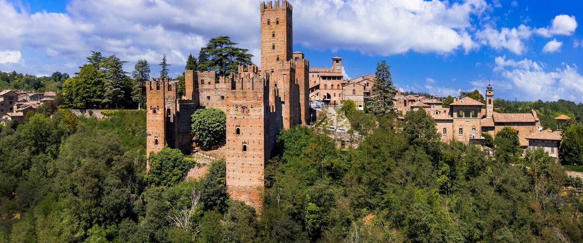 A historic castle surrounded by lush greenery and a clear blue sky.