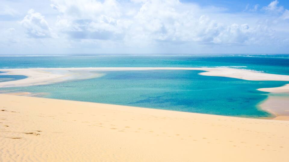A beach with clear turquoise waters and white sand.