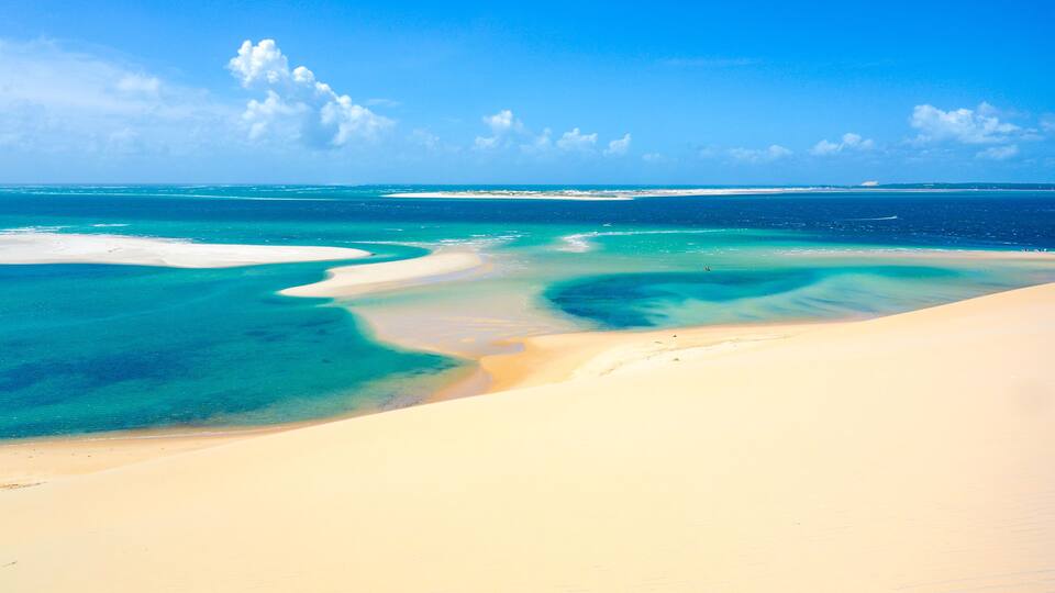 A beach with clear turquoise waters and white sand.