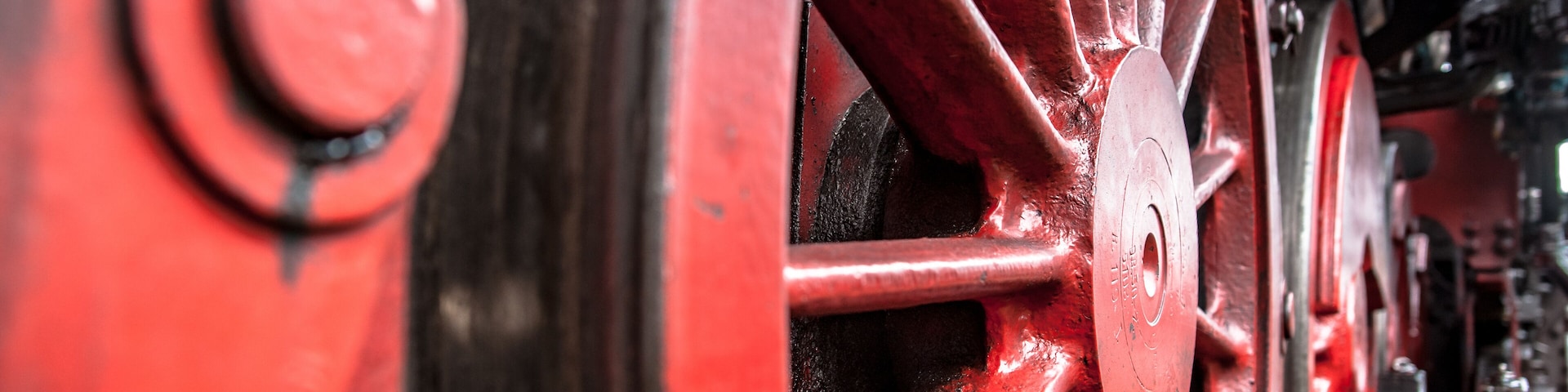 A close-up of a red metal wheel with bolts and a circular component.