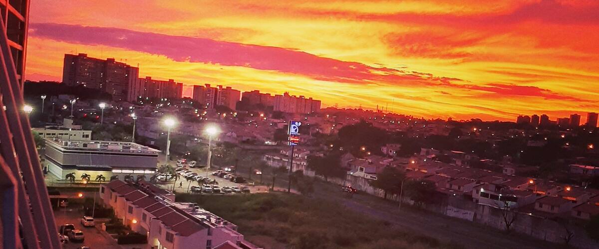 A sunset over a cityscape with buildings and a parking lot.