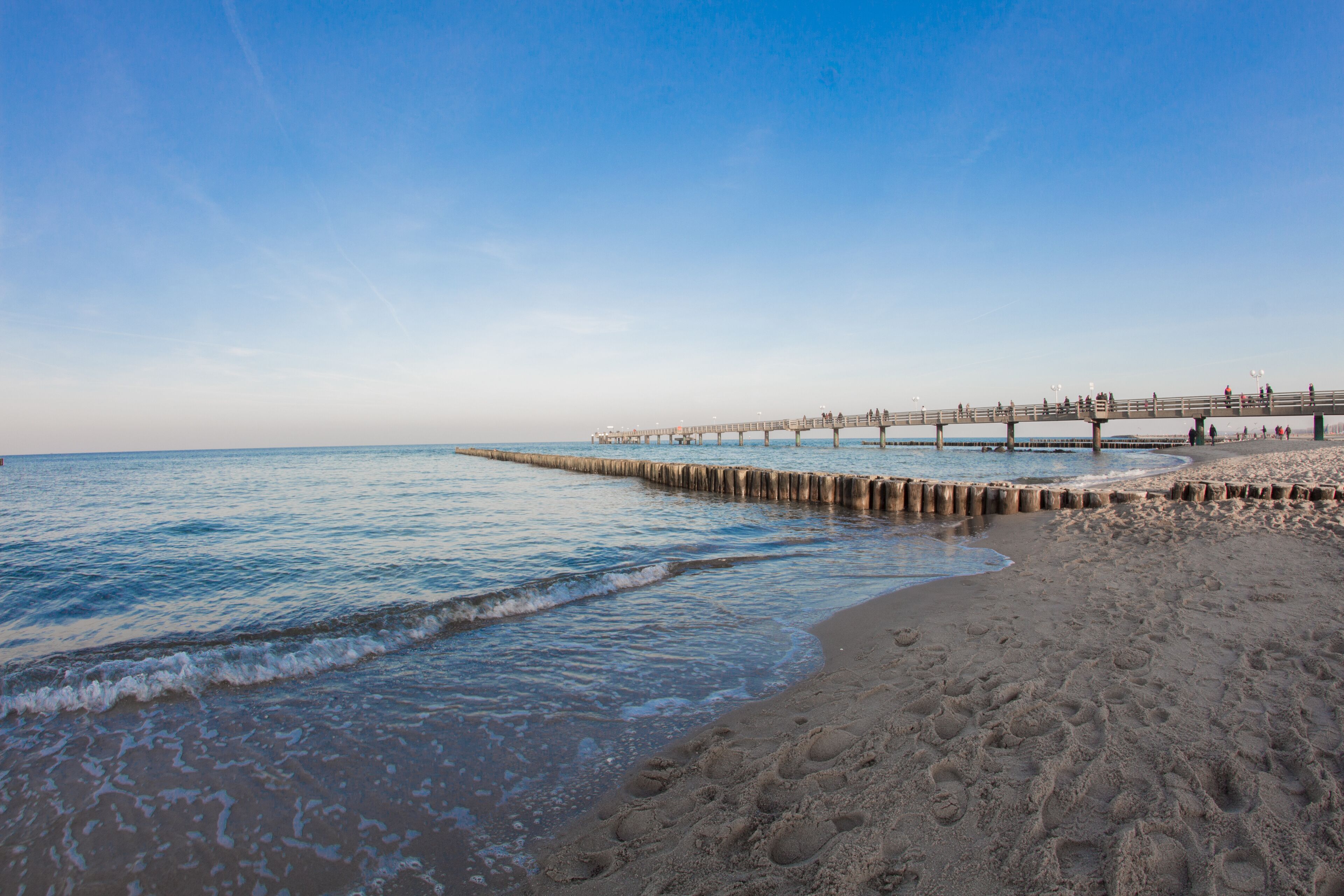 A beach with a wooden pier extending into the ocean.