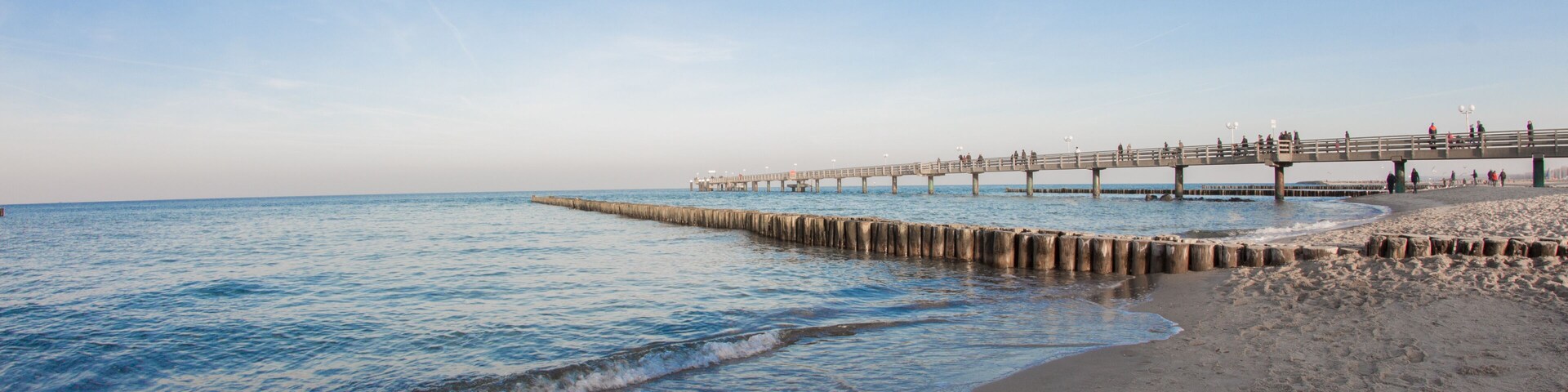 Una playa con un muelle de madera que se adentra en el océano.