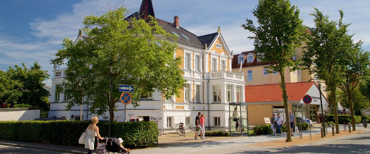 A street with a building, trees, and people walking.
