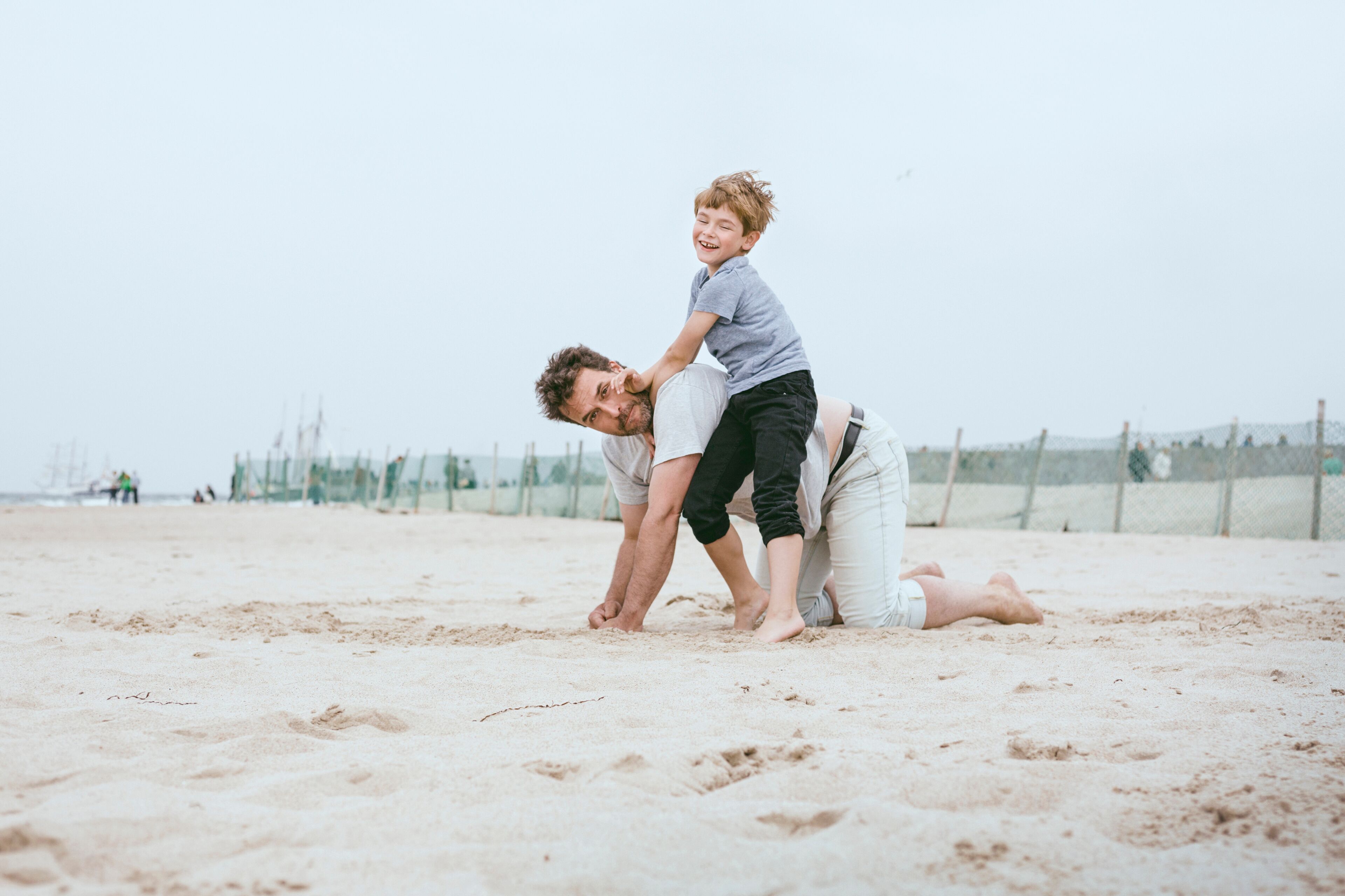 Father and little son playing together on the beach