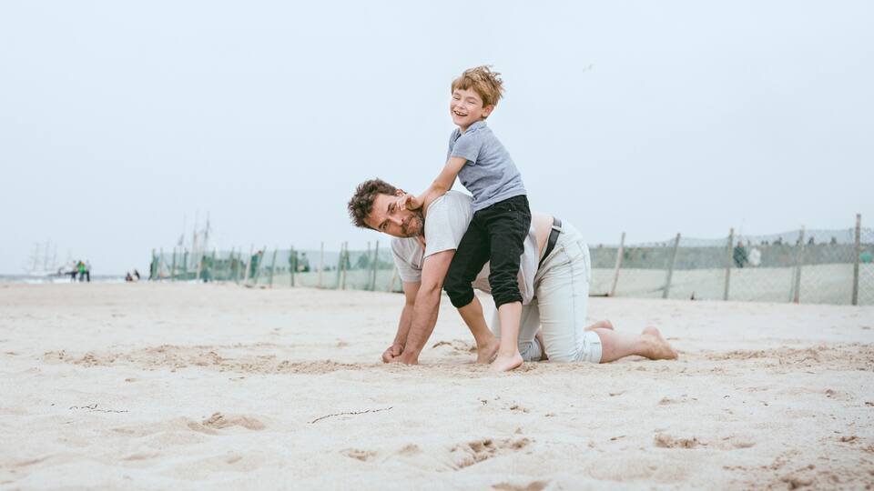 A sandy beach with a fence in the background.