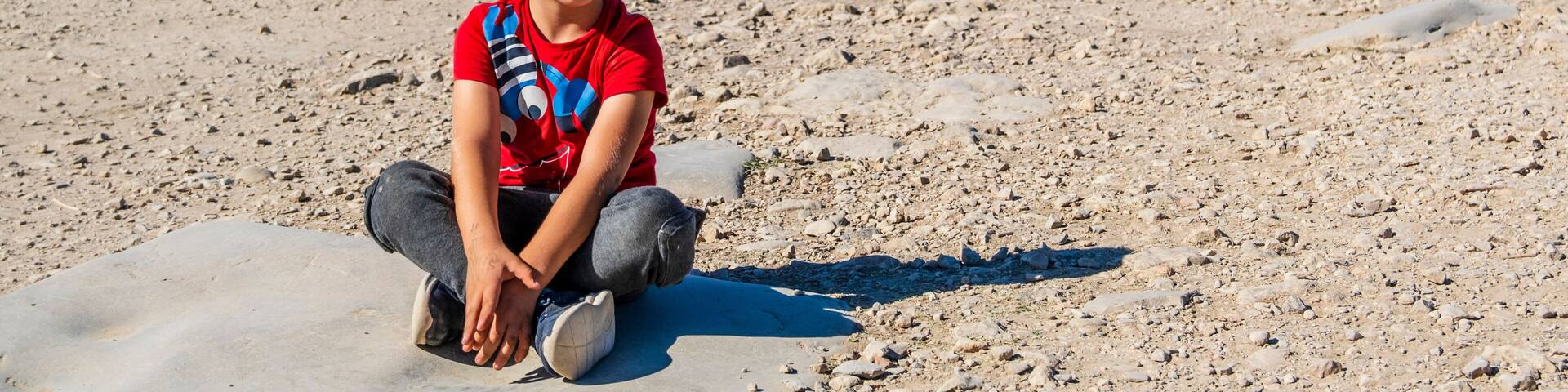 A boy sitting among well-preserved roman ruins in Volubilis, Fez Meknes area, Morocco