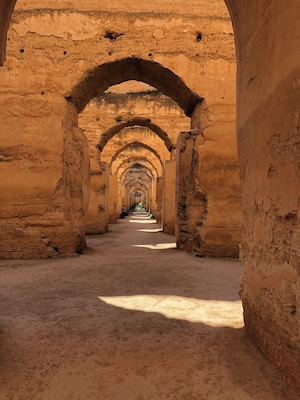 Un largo pasillo con arcos y piso de tierra.
