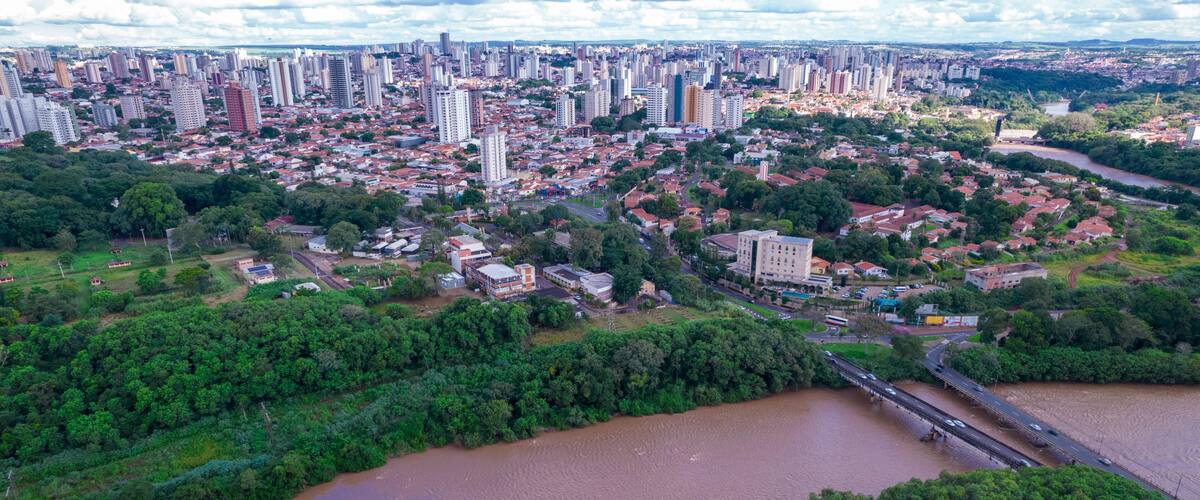 A river flowing through a city with dense greenery and high-rise buildings.