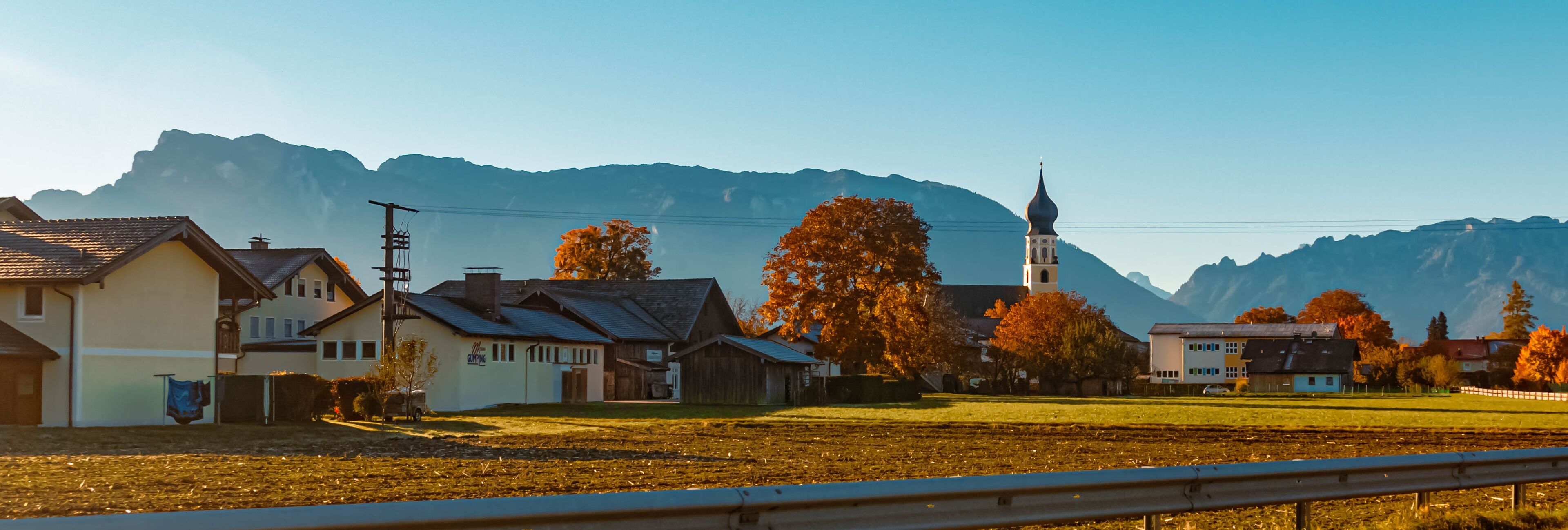 A rural village with houses, a church, and mountains in the background.
