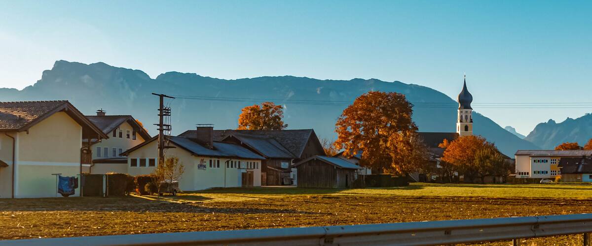 A rural village with houses, a church, and mountains in the background.