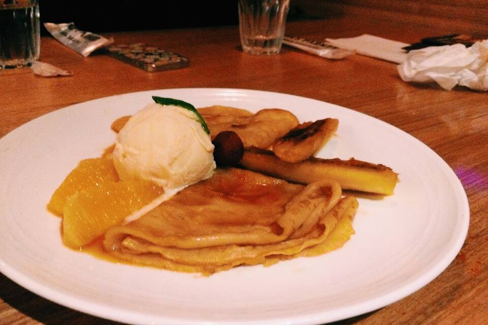 A plate with pancakes, a scoop of ice cream, and a slice of fruit.