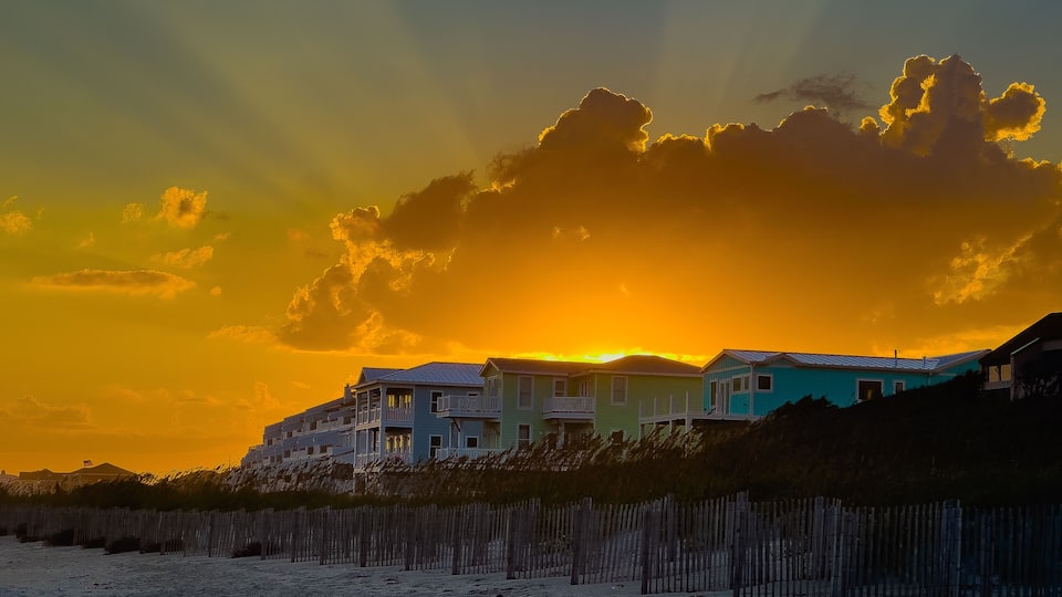 A beach with houses and a wooden fence.