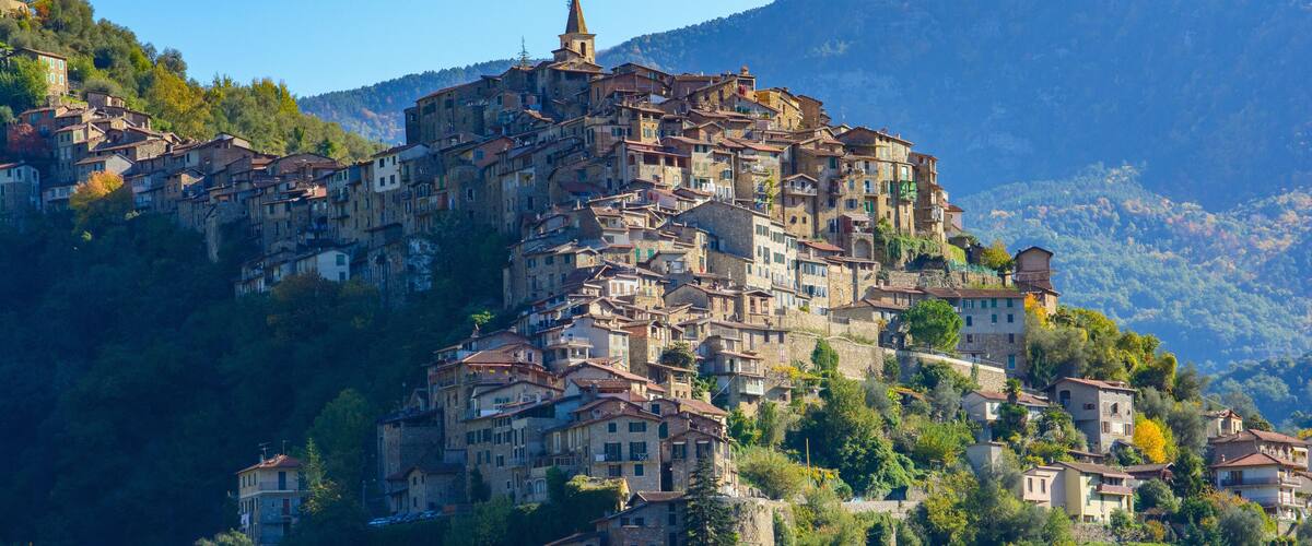A hillside village with historic buildings nestled among trees and mountains.