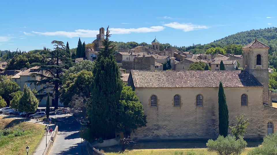A historic town with a prominent church featuring a bell tower, surrounded by lush greenery and rolling hills.