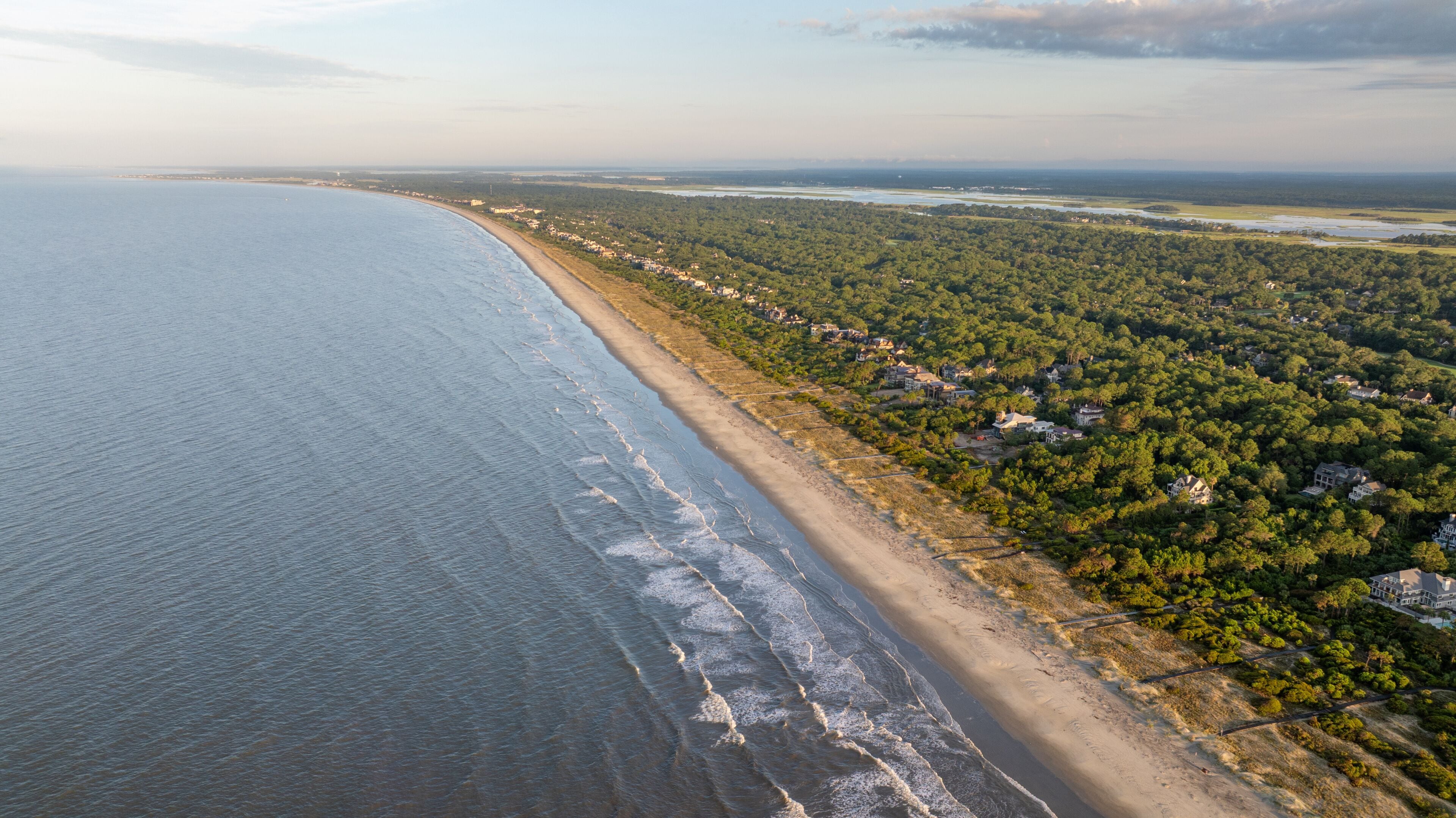 Aerial view of beachfront mansion homes along Kiawah Island ocean landscapes near Charleston, South Carolina showcasing the lowcountry coast and natural beauty during morning sunrise - 4K Drone