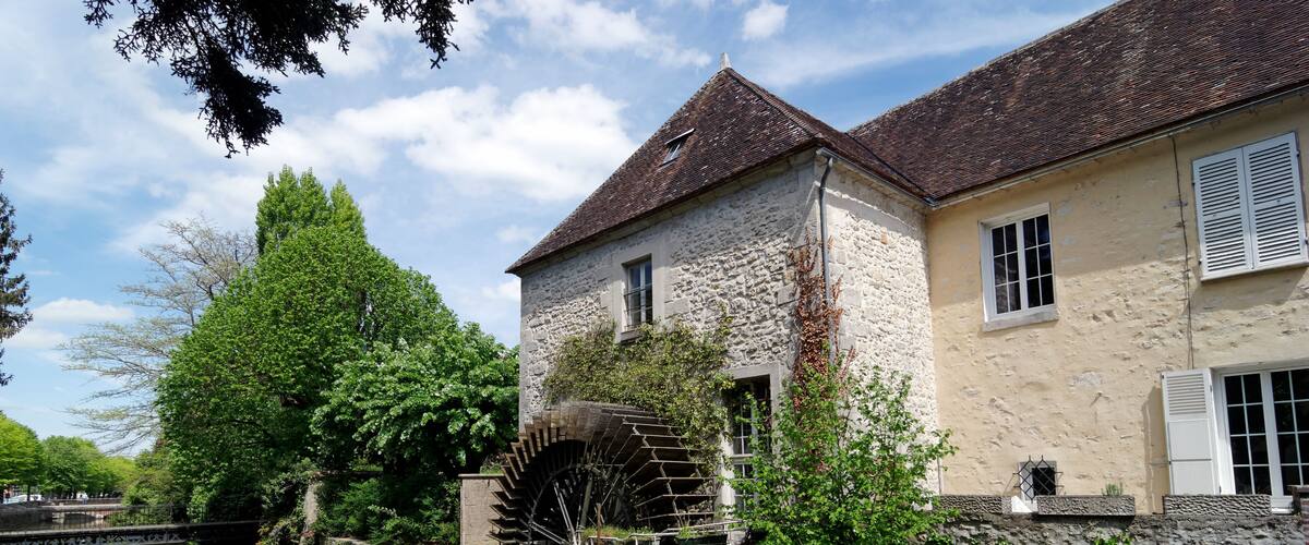 A historic stone building with a water wheel and a river.