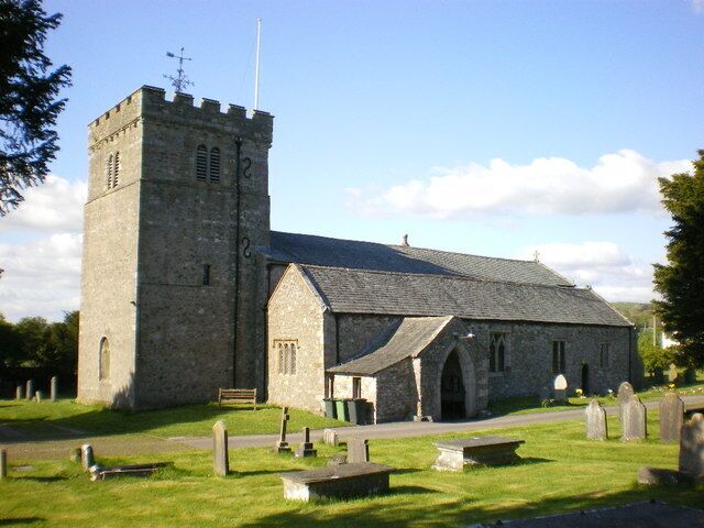 A stone church with a bell tower and a cemetery in front.