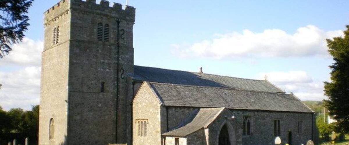 A stone church with a bell tower and a cemetery in front.