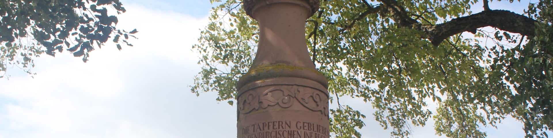Denkmal für Gefallene des 3. Brandenburgischen Infanterie-Regiments No. 20 im Krieg von 1866. Runder Pfeiler mit achteckigem Sockel und Pickelhaube an der Spitze. Inschrift: DIE TAPFERN GEBLIEBENEN DES BRANDENBURGISCHEN INF. REGIMENTS No. 20. / 1866. / SECOND LIEUTNANT: / MAX KROHN AUS WERBEN BEI ZOSZEN. / DIE GEFREITEN: / JOHANN FRIDRICH KOHL AUS BARDEWITZ. / WILHELM GECK AUS ISERLOHN. / FRANZ HÜLLEN AUS BERLIN. / GOTTHELF LEITEL AUS MESERITZ. / DIE MUSKETIERE: / EDUARD SIEGNER AUS BEELITZ. / JOHANN GOTTLIEB MITTAG AUS BAERWALDE. / FRIDRICH WILHELM MÜLLER AUS DOBRILUCK. / JOHANN FRIDRICH FISCHBECK AUS EERCH. / GOTTFRID ALBERT HOHENSCHILT AUS SHLUNKENDORF. / EDMUND EMIL RUDOLPH FISCHER AUS BERLIN. / DIE FÜSILIERE: / PETER EICHELBAUM AUS NESCHHOLZ. / ERNST KUBAT AUS RATZEBUR. / CARL WILKE AUS BERLIN.