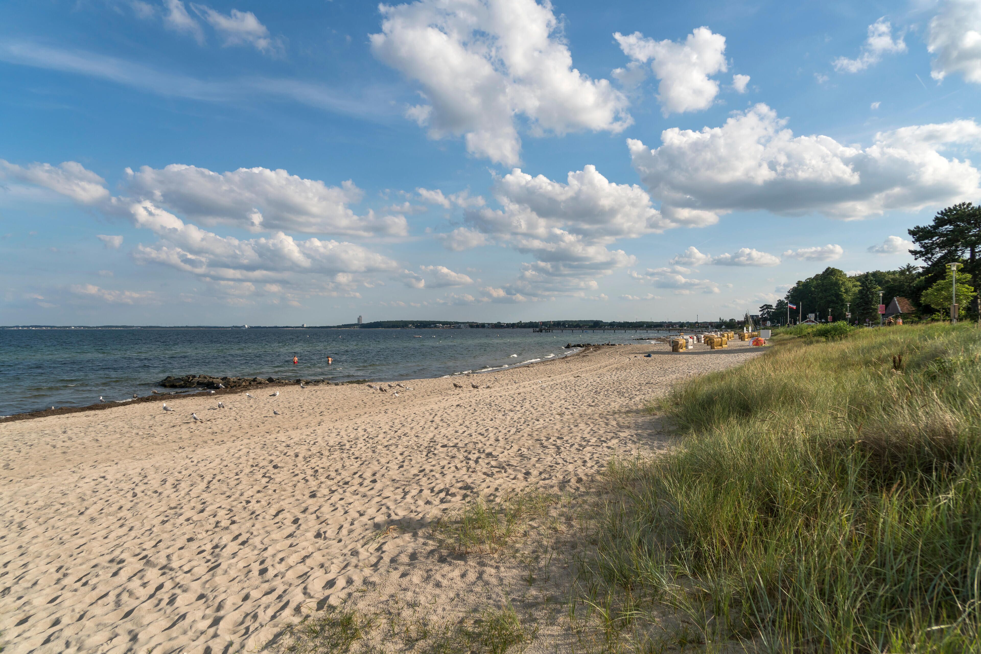 A sandy beach with a clear sky and scattered clouds.