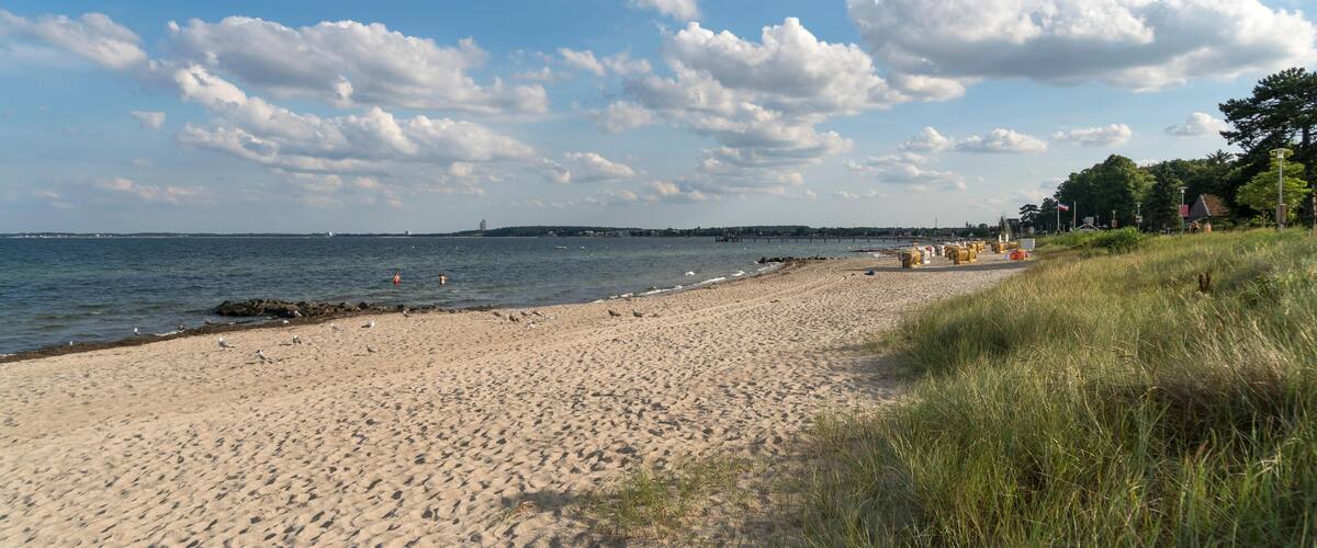 A sandy beach with a clear sky and scattered clouds.