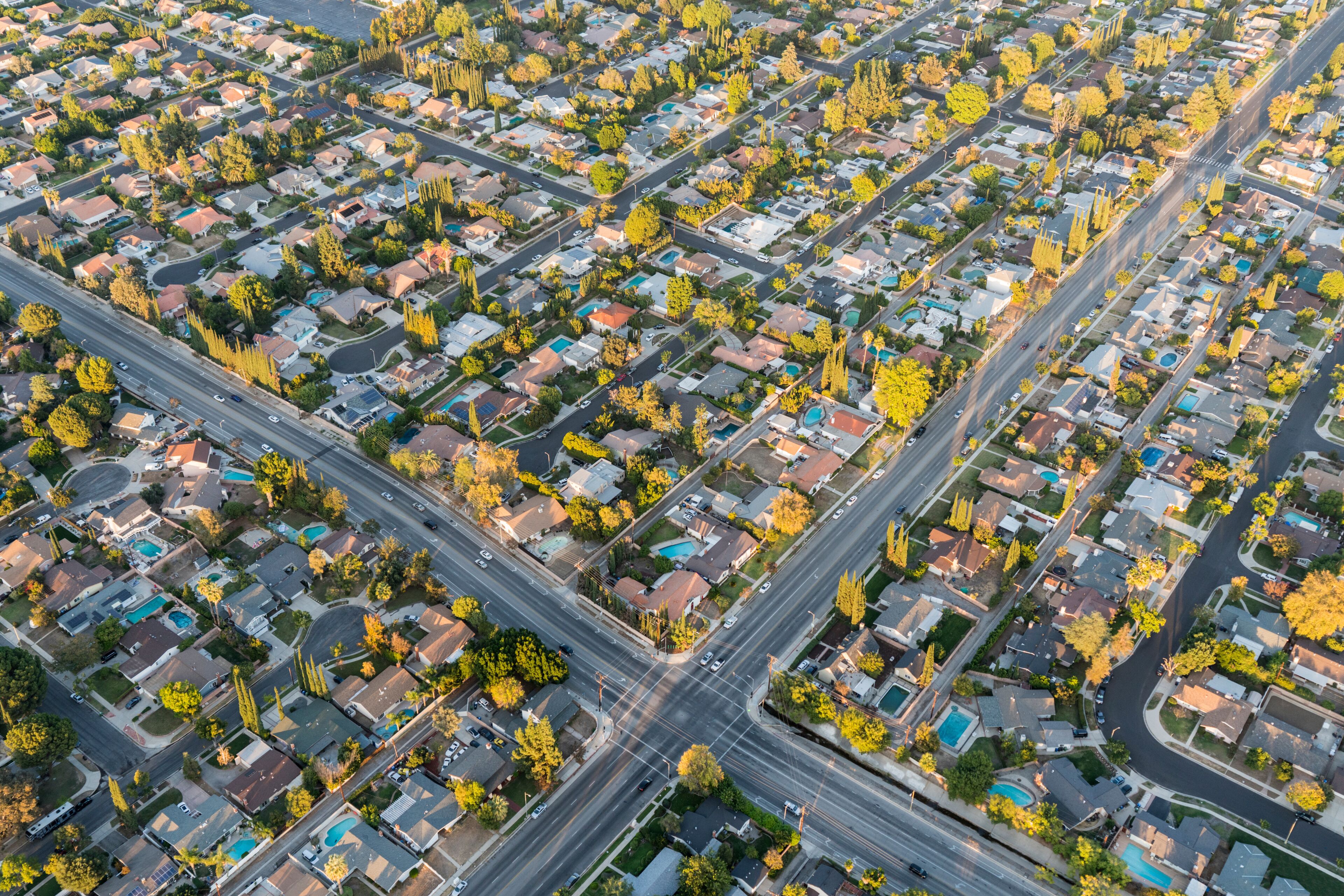 An aerial view of a residential area with houses, roads, and trees.