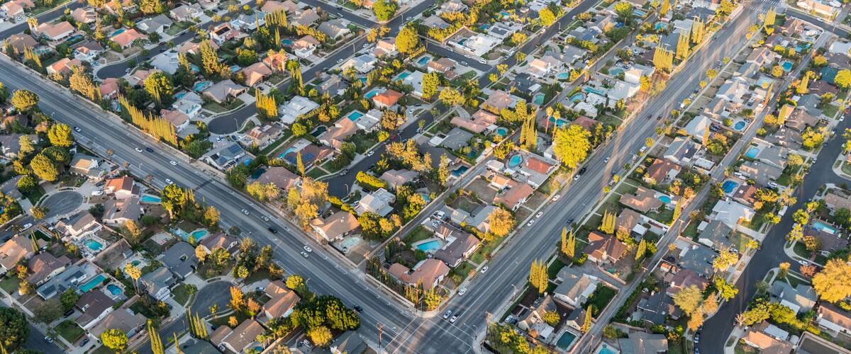An aerial view of a residential area with houses, roads, and trees.