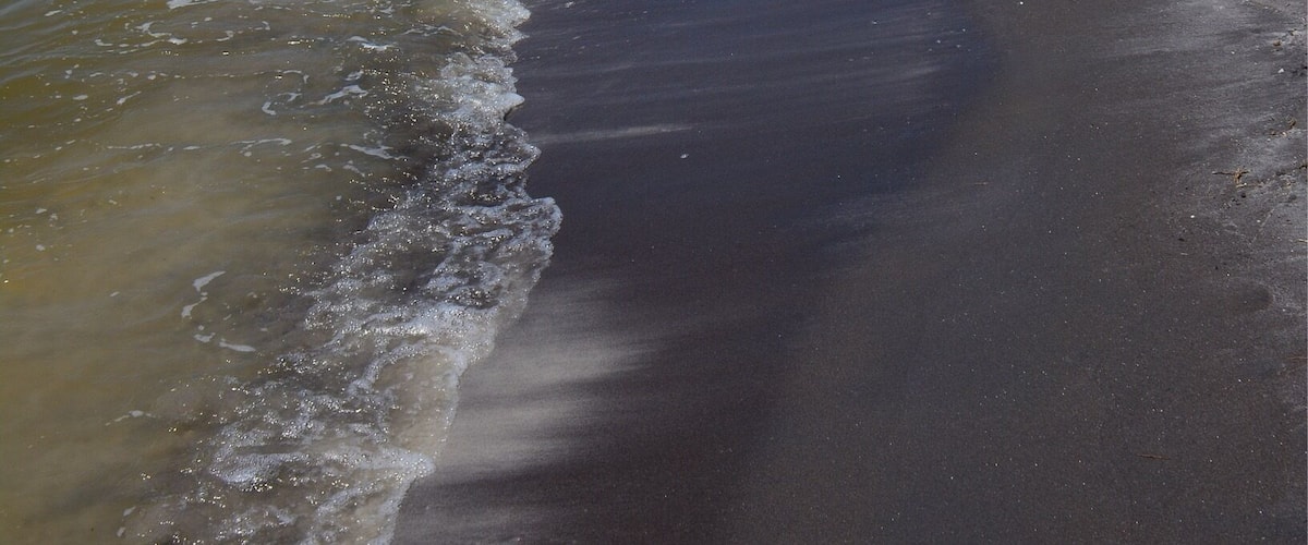 A beach with clear blue water and a sandy shore.