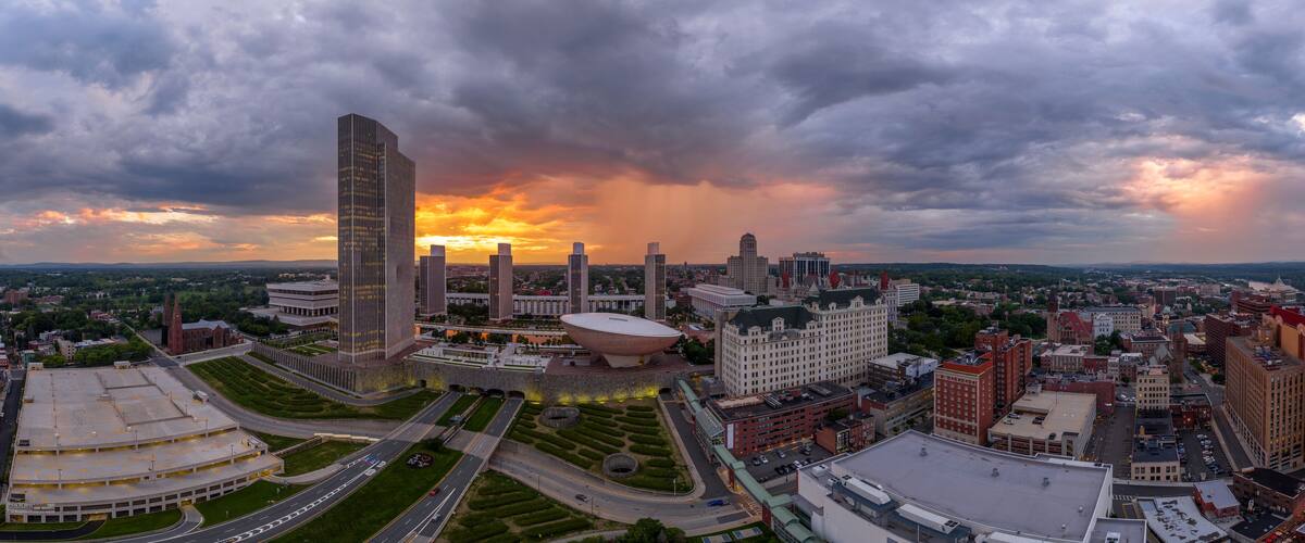 A cityscape with a large modern building, a dome-shaped structure, and a historic church.