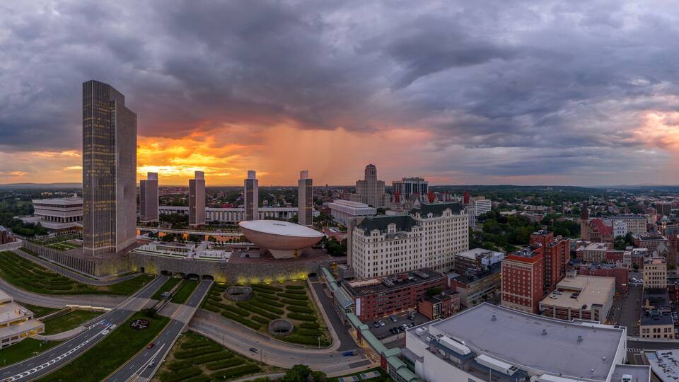 A cityscape with a large modern building, a dome-shaped structure, and a historic church.