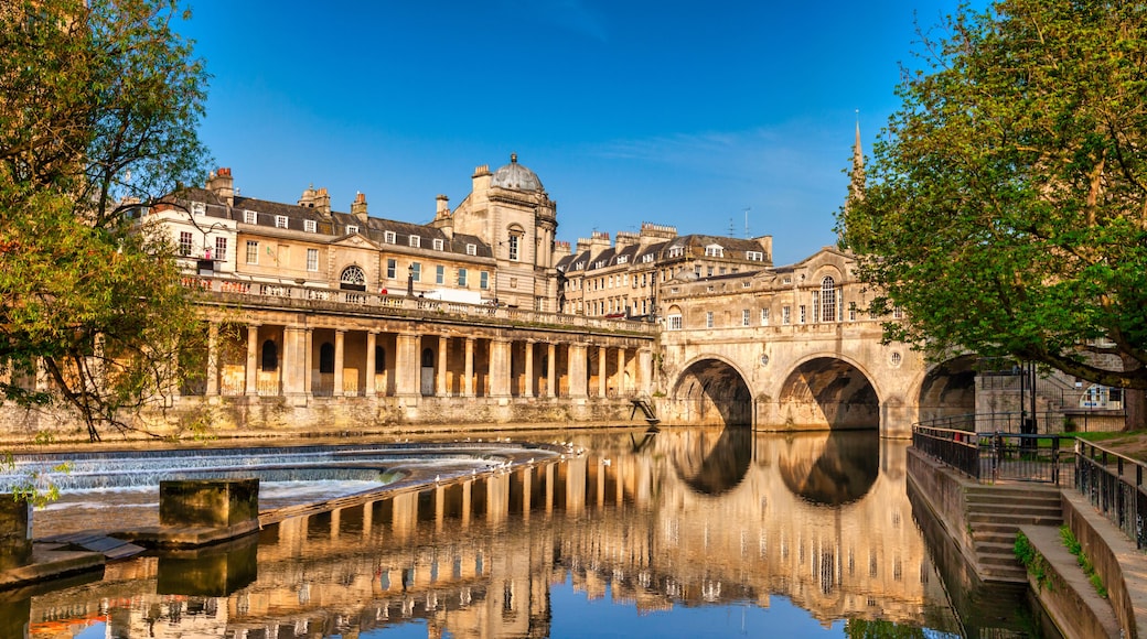 Un edificio histórico con puentes arqueados sobre un río tranquilo, que refleja la arquitectura.