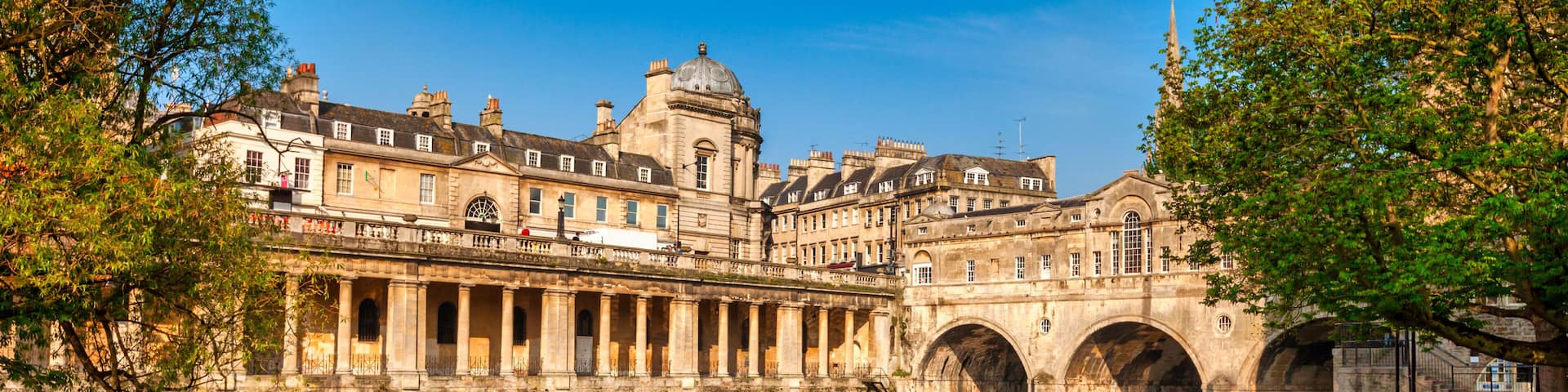 A historic building with arched bridges over a calm river, reflecting the architecture.