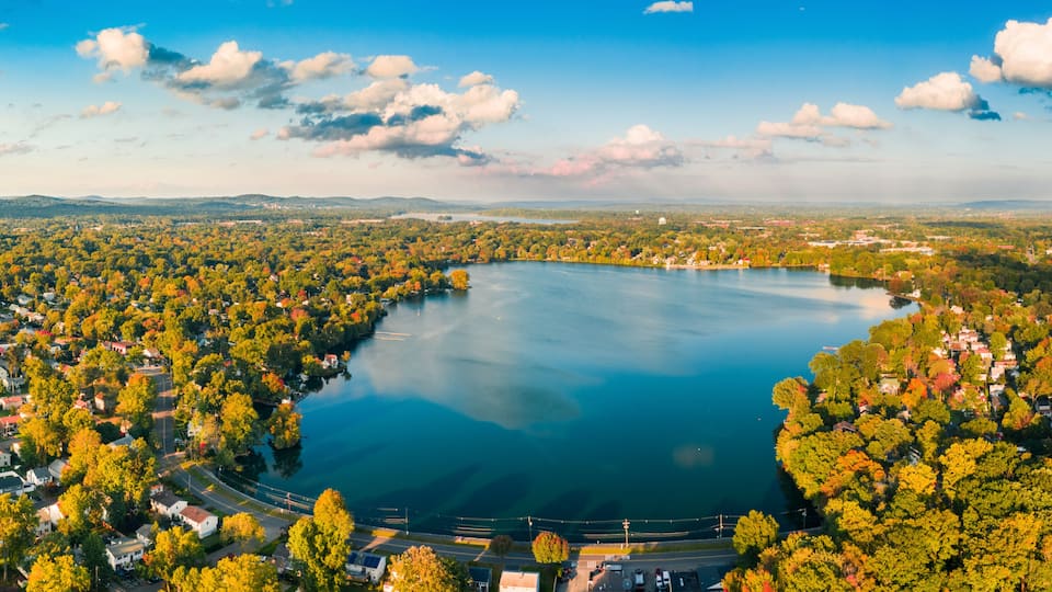 A large lake surrounded by dense forest and residential areas.