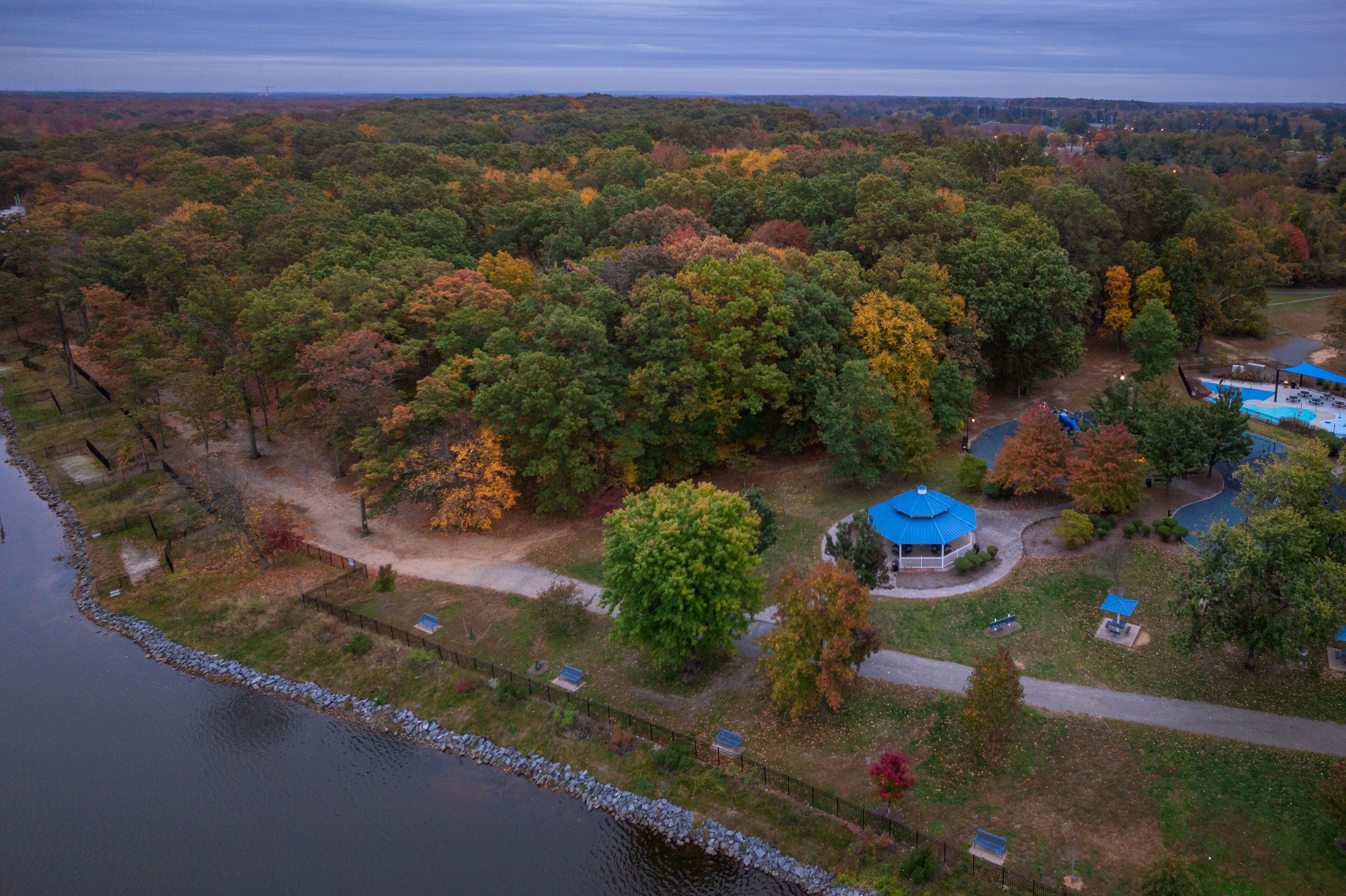 Una propiedad junto al lago con un quiosco, piscina y zona boscosa.
