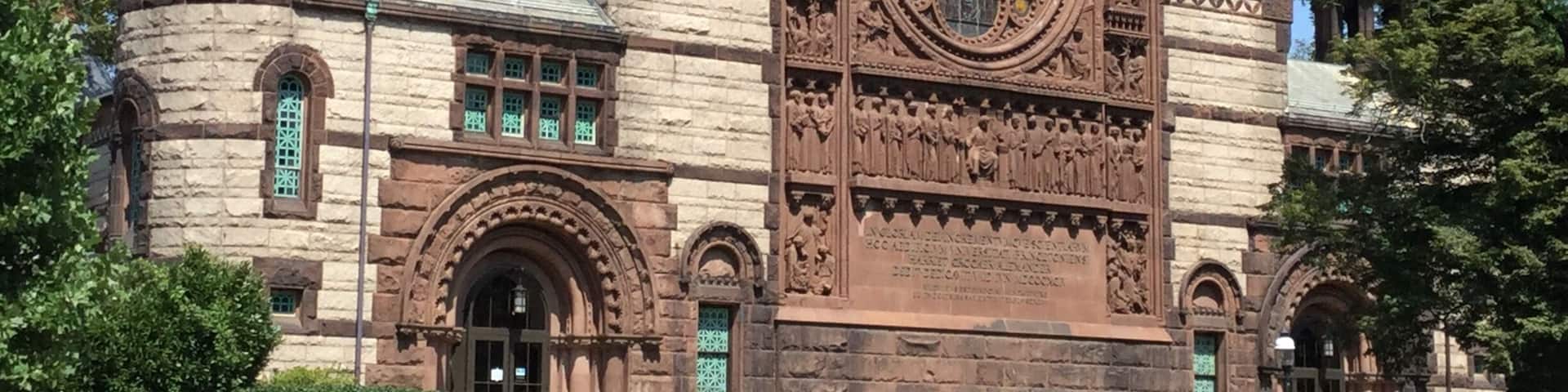 A historic building with a large arched window, stone towers, and intricate carvings.