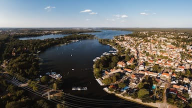 Vista aérea de uma cidade à beira de um lago, com barcos atracados na margem e uma área residencial densa, com casas de telhado vermelho.