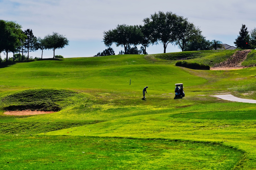 Silhouette of a Golfer and Golf Cart Midway on an Uphill Hole of a Golf Course