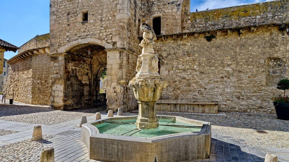 A historic stone building with a fountain in the foreground.