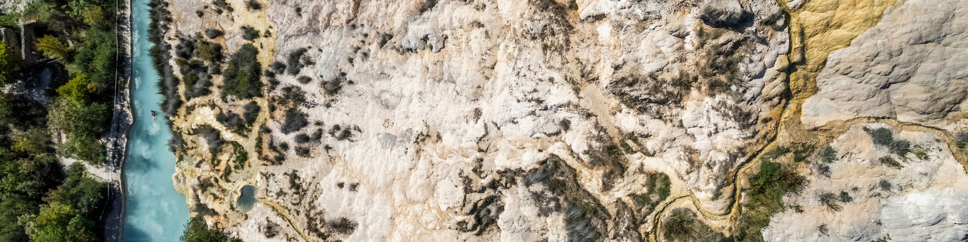 An aerial view of a river winding through a rocky landscape with sparse vegetation.