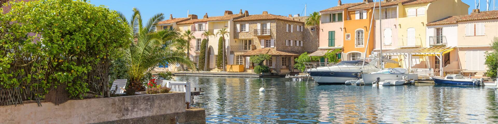 A calm harbor with boats, colorful buildings, and lush greenery.