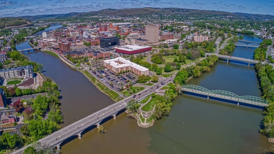 An aerial view of a city with a river, bridges, and surrounding greenery.