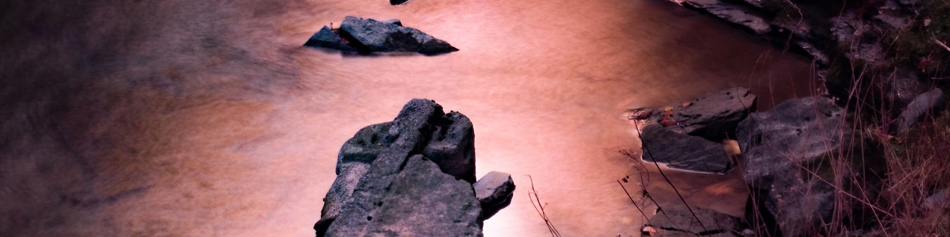 Um riacho pedregoso com água corrente sobre pedras.