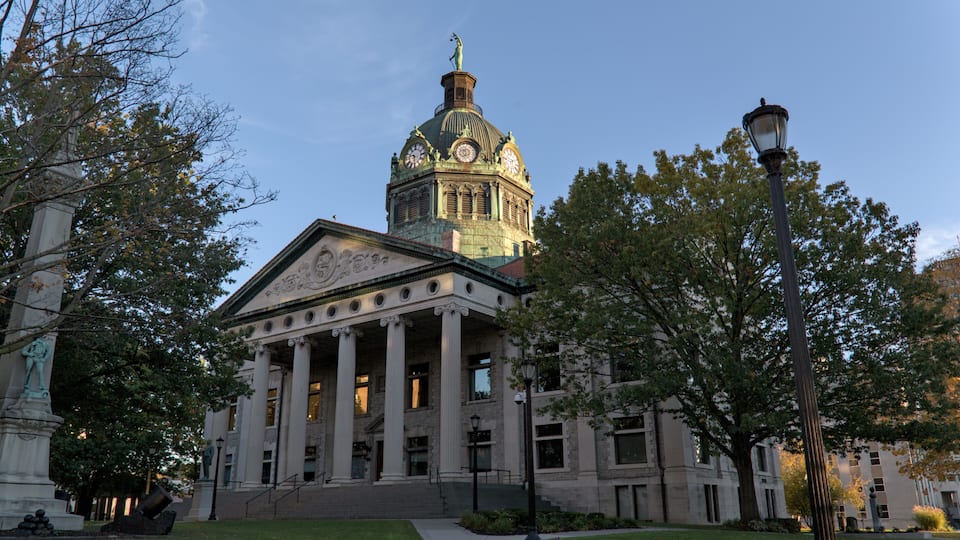 A neoclassical building with a dome and columns, surrounded by trees and a well-maintained lawn.