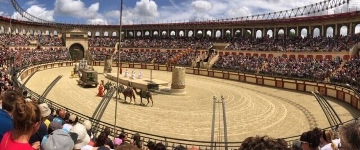 A bullfighting arena with a circular ring, a central platform, and a crowd of spectators.