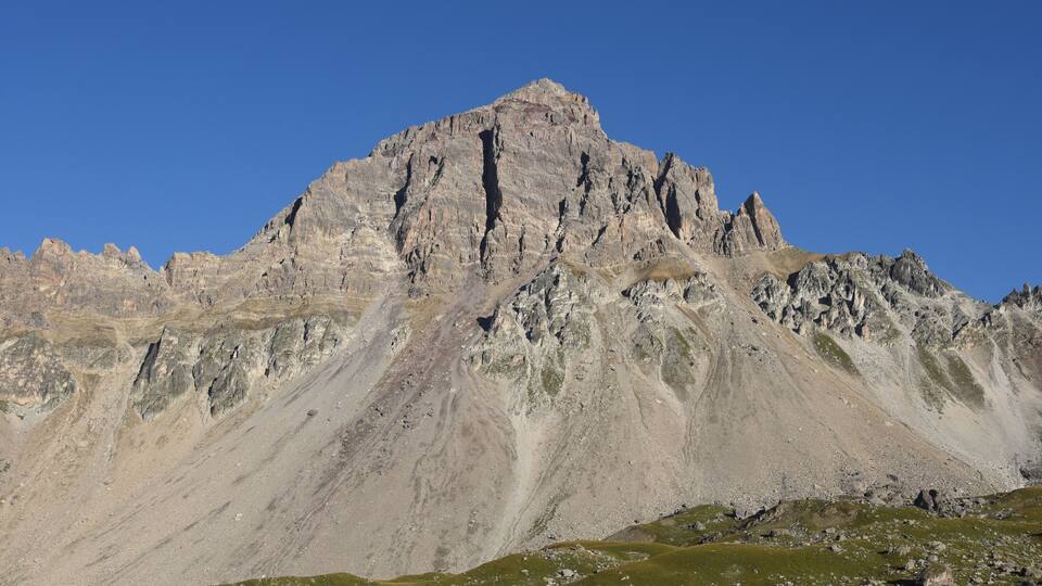 A rugged mountain peak with a clear blue sky.