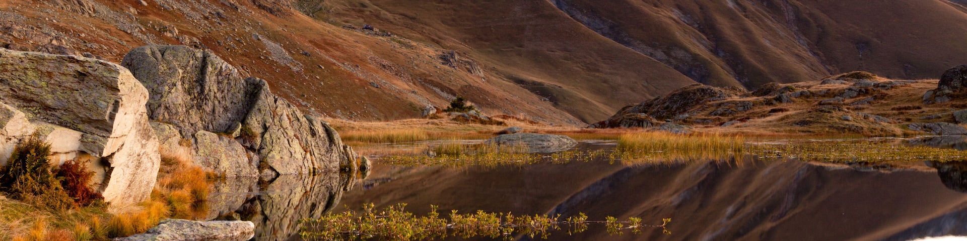 Paisagem montanhosa com um lago espelhado.