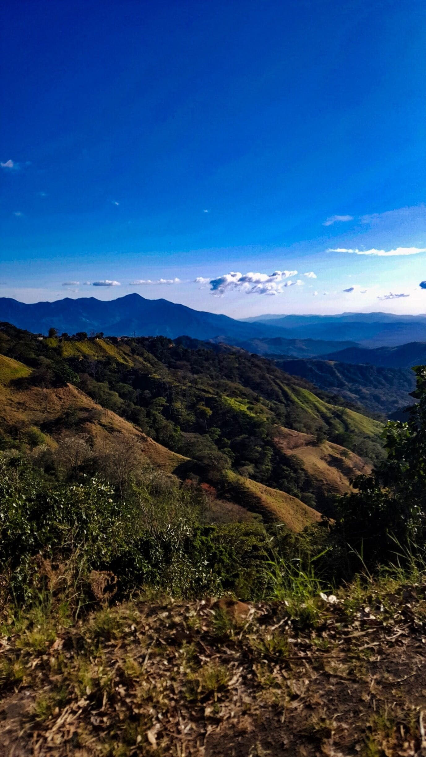 A mountainous landscape with rolling hills and a clear blue sky.